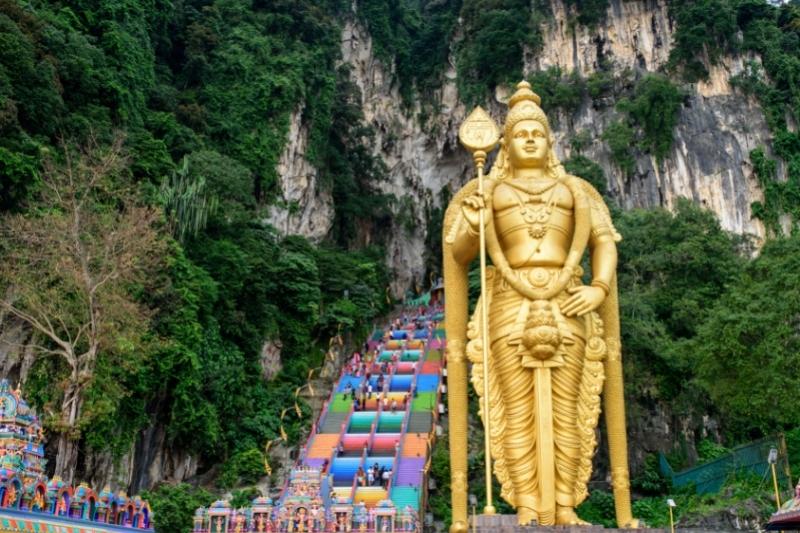 Pemandangan luar kawasan kuil Batu Caves dengan bukit kapur dan patung Dewa Murugan di Malaysia